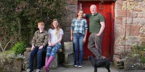Lee Family of Torepenhow Farmhouse Diary outside the farmhouse with their black dog